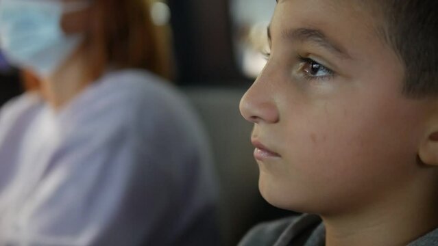 Close-up of a boy's face while he watches and play arcade game and talks to his mother.