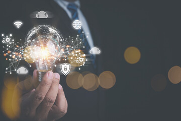 Businessman holding a lightbulb with connection technology digital internet network with technology icons black background. Creative idea and innovation technology concept.