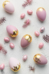 Easter eggs are painted with violet and gold paint on a gray concrete background.