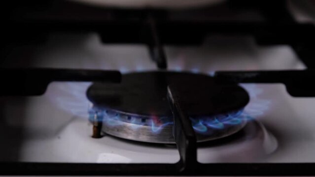 Ignition of the gas burner on the stove in the kitchen. Use of natural resources, economy, cooking on fire. Close-up