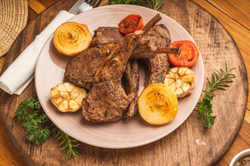 Lamp Rack Steak or Lamb chops Steak with rosemary, onion and tomato on wooden background.