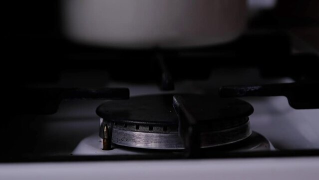 Ignition of the gas burner on the stove in the kitchen. Use of natural resources, economy, cooking on fire. Close-up