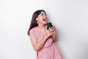 Portrait of carefree Asian woman, having fun karaoke, singing in microphone while standing over...