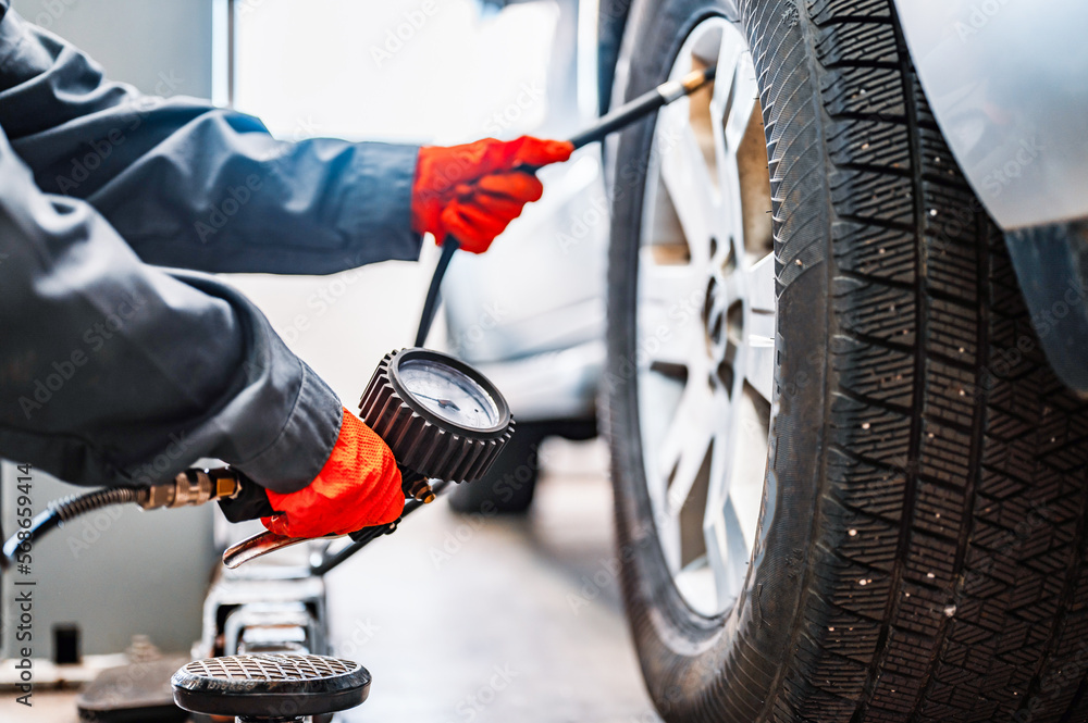 Wall mural inflating tire and checking air pressure use gauge in mechanics hands. Car service, checking vehicle