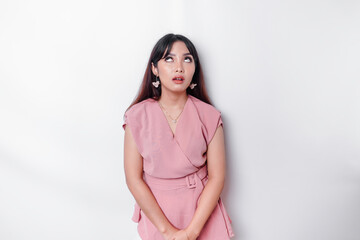 Dissatisfied young Asian woman dressed in pink blouse rolling her eyes and raising hand...
