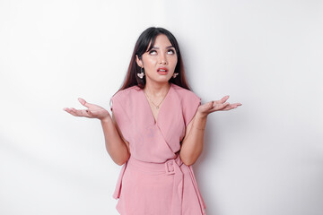 Dissatisfied young Asian woman dressed in pink blouse rolling her eyes and raising hand...