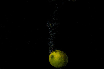 Fototapeta na wymiar fresh fruits falling in water with splash on black background.