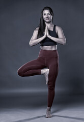 Woman doing yoga vrksasana pose, monocrome toned