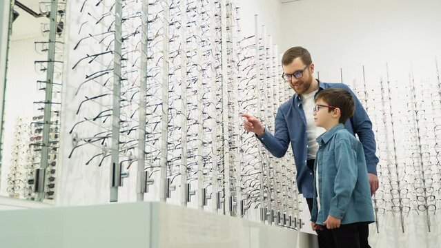 Little boy in optics store choosing glasses with his father. Ophthalmology concept