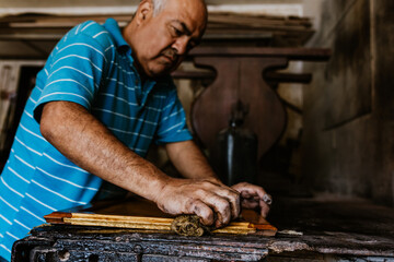 hands of Hispanic Senior man carpenter making wooden window in his workshop in Mexico Latin America