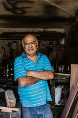 portrait of hispanic senior man carpenter working in the wood at the furniture workshop in Mexico Latin America