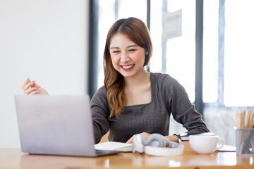 Young adult happy smiling Hispanic Asian student video calling on laptop or doing video chat by webcam in university campus or virtual  at office. College female student learning remotely.