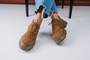 Close-up of female legs in blue jeans and suede brown sneakers. Women's leather casual sneakers