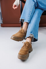 Close-up of female legs in blue jeans and suede brown sneakers. Women's leather casual sneakers