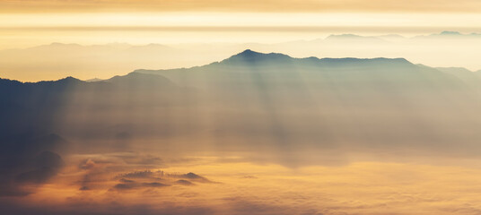 Panorama landscape of mountain in morning sunrise.Sunray over the mist in evening.Layers of mountains in orange background at sunset time.