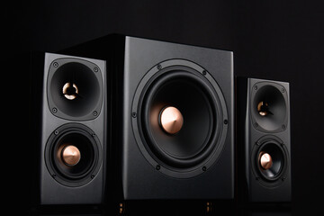 Two sound speakers and subwoofer on dark background. Set for listening music. Audio equipment