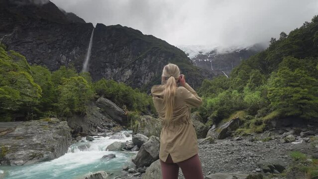 Blond female nature photographer stepping into frame at Rob Roy glacier valley