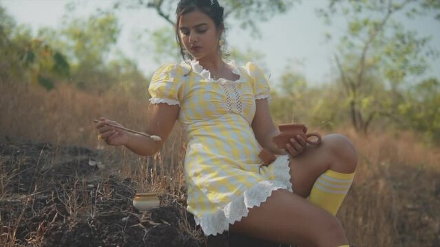 Wide Shot Of Young Beautiful Indian Woman Dipping A Brush Into A Pot Resting On The Ground While Fixing A Broken Clay Pot. Slow Motion.