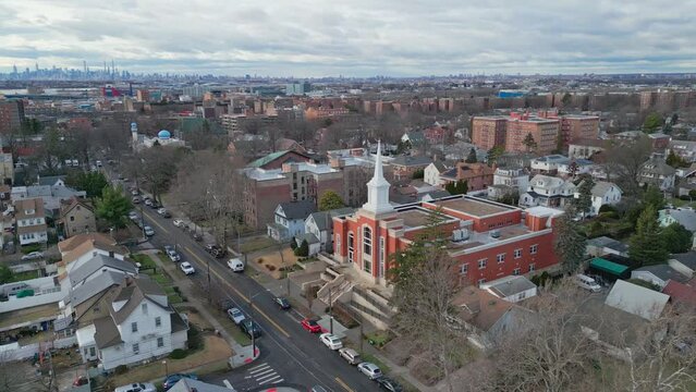 Aerial orbiting shot of church in Queens District with skyline of Manhattan in background during cloudy day