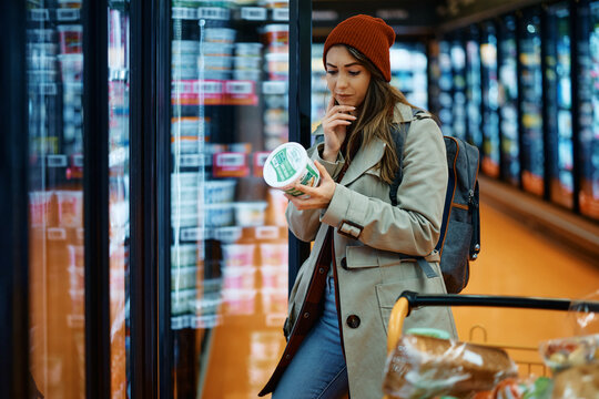 Young Woman Buys Dairy Product And Reads Food Label In Grocery Store.