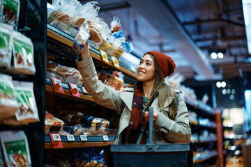 Fototapeta premium Happy woman buying pastry in grocery store.