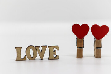 Wooden inscription and clothespins with hearts on a white background