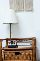 Vintage rattan chair with lamp and books on white wall background