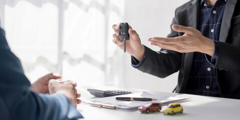 Car rental and Insurance concept, Young salesman giving car is key to customer after sign agreement contract with approved for rent or purchase.