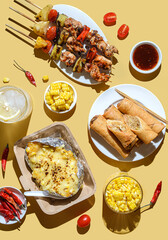 kebabs on skewers spring rolls and corn