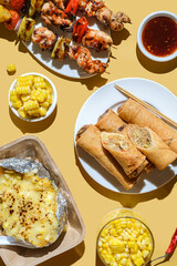 kebabs on skewers spring rolls and corn