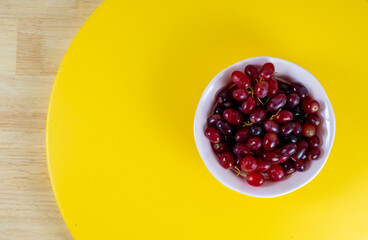 Red grapes on pink cup, yellow background