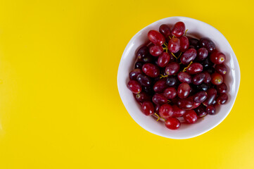 Red grapes on pink cup, yellow background