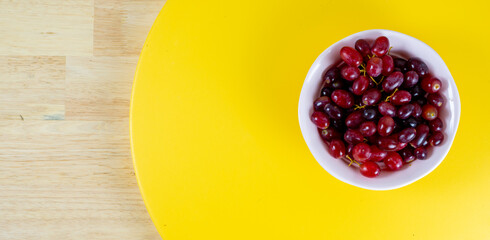 Red grapes on pink cup, yellow background