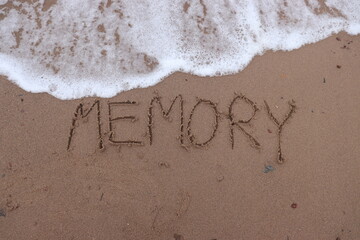 Writing the letters m e m o r y or memory on the sand and the sea water is flowing to erase this...
