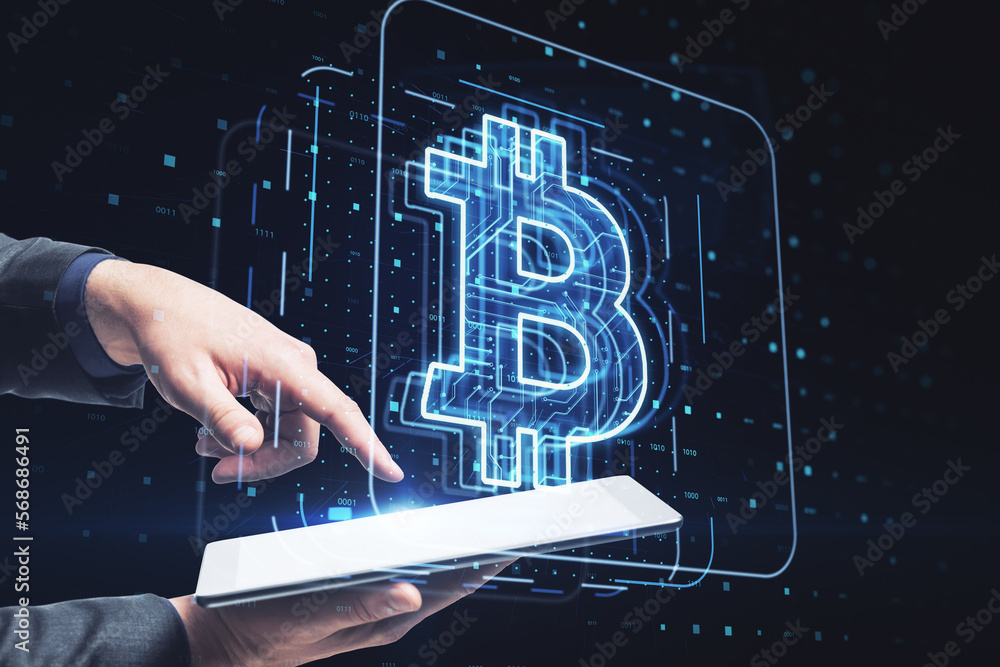 Poster close up of businessman hand holding and pointing using cellphone with glowing bitcoin hologram on d
