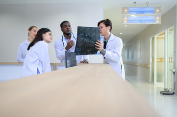 Medical teacher and interns analyzing the x-ray results of the patient's brain. before major...