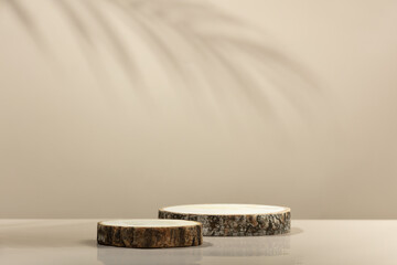 Wood slice podiums and leaves shadow on beige background for cosmetic product mockup