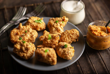 Pieces of flour-fried cauliflower with vegan sauces on a plate on a dark background. Cauliflower wings food.