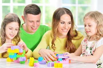 Naklejka premium Girl with mother and father playing with wooden blocks