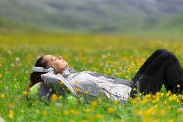 Hiker resting listening to music lying on field