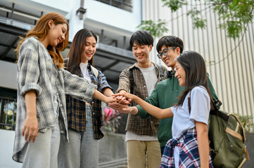 Group of happy Asian college students putting their hands together. success team building concept