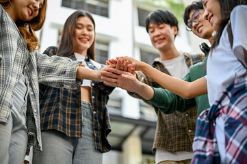 Group of cheerful Asian college students putting their hands together. friends, unity, teamwork