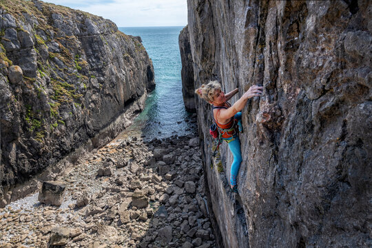 Mature athlete climbing rocky wall