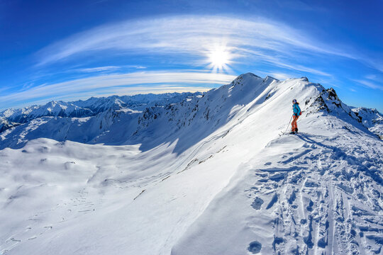 Austria, Tyrol, Sun shining over female skier admiring snowcapped landscape in Tux Alps