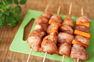 Cooking chicken fillet kebab with vegetables - raw meat on skewers on a table on the background of an aged tree. Selective focus. Close-up. 