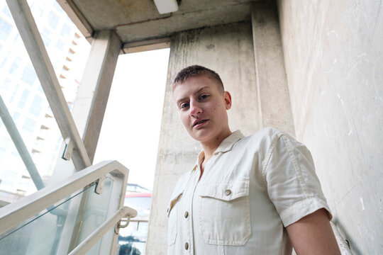 Smiling non-binary person standing in front of wall