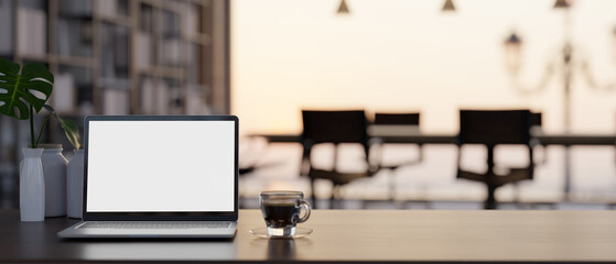 Workspace tabletop with laptop mockup and copy space over blurred meeting room background