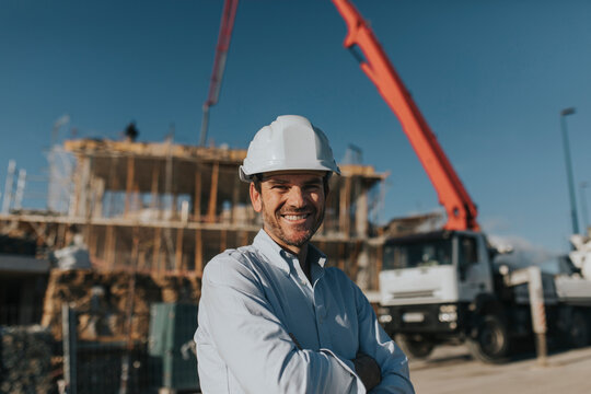 Happy mature architect wearing hardhat at construction site
