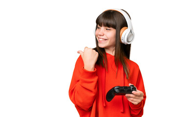 Little caucasian girl playing with a video game controller over isolated background pointing to the side to present a product