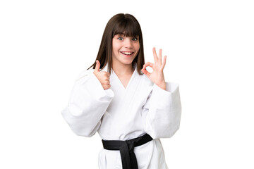 Little Caucasian girl doing karate over isolated background showing ok sign and thumb up gesture